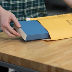 A blue book is unpacked from inside a bubble kraft mailer.